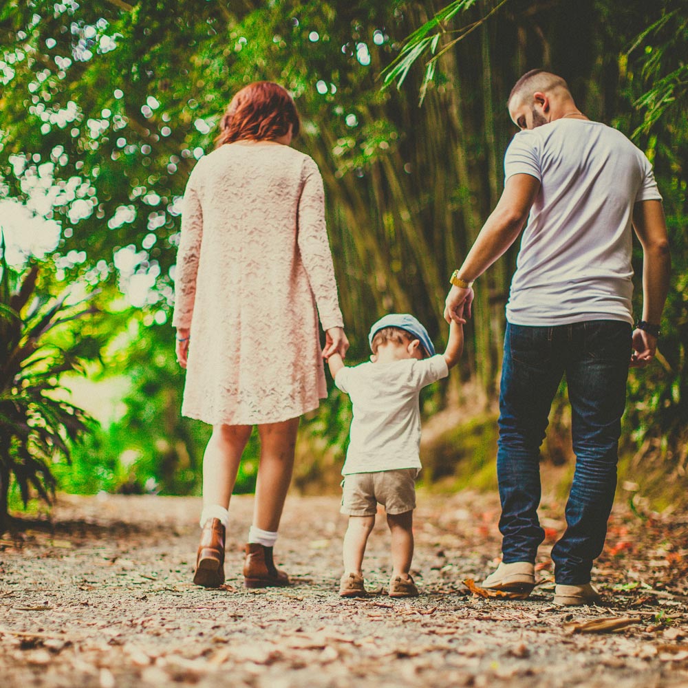 Image of couple and toddler walking down a shaded path.