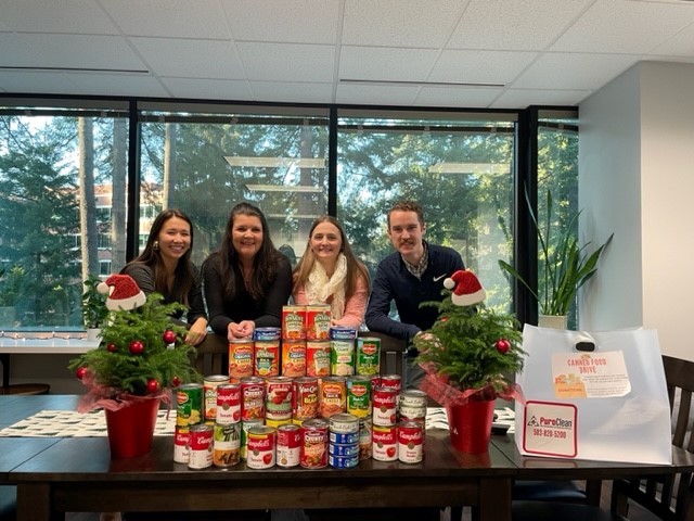 Picture of Frinell team members with canned food collected for canned food drive.